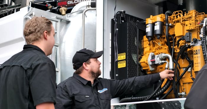 PS Equipment technicians inspecting a Caterpillar engine on a hydro excavation truck.